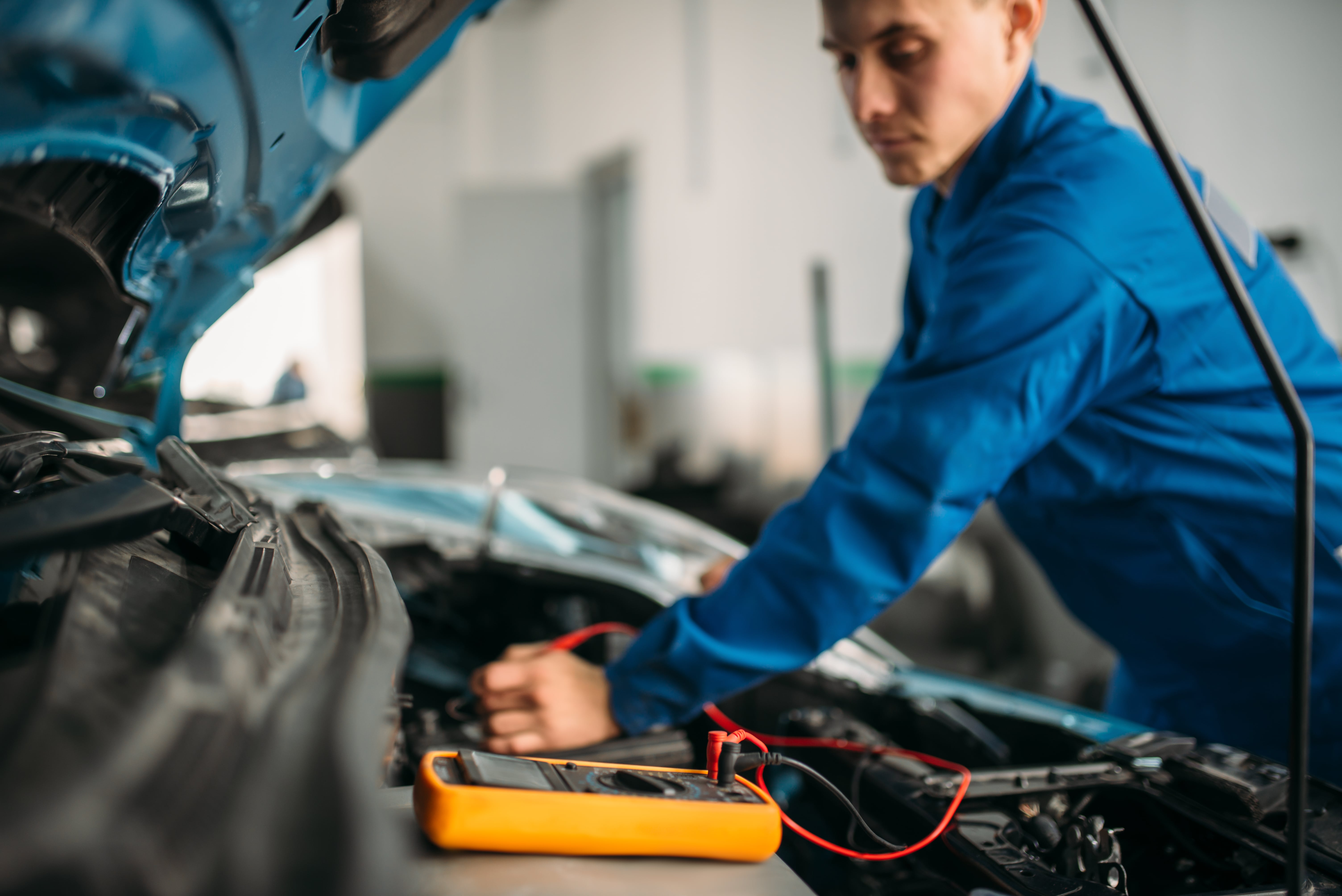 car repairman with multimeter battery inspection WH3XLNC